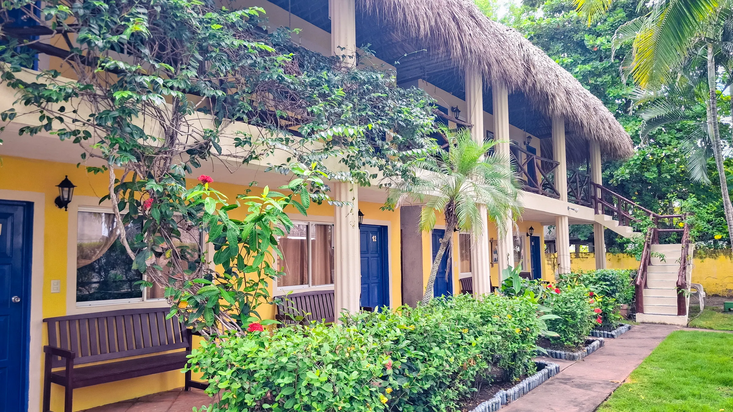 Edificio de habitaciones con techo de palma, corredores y jardín.