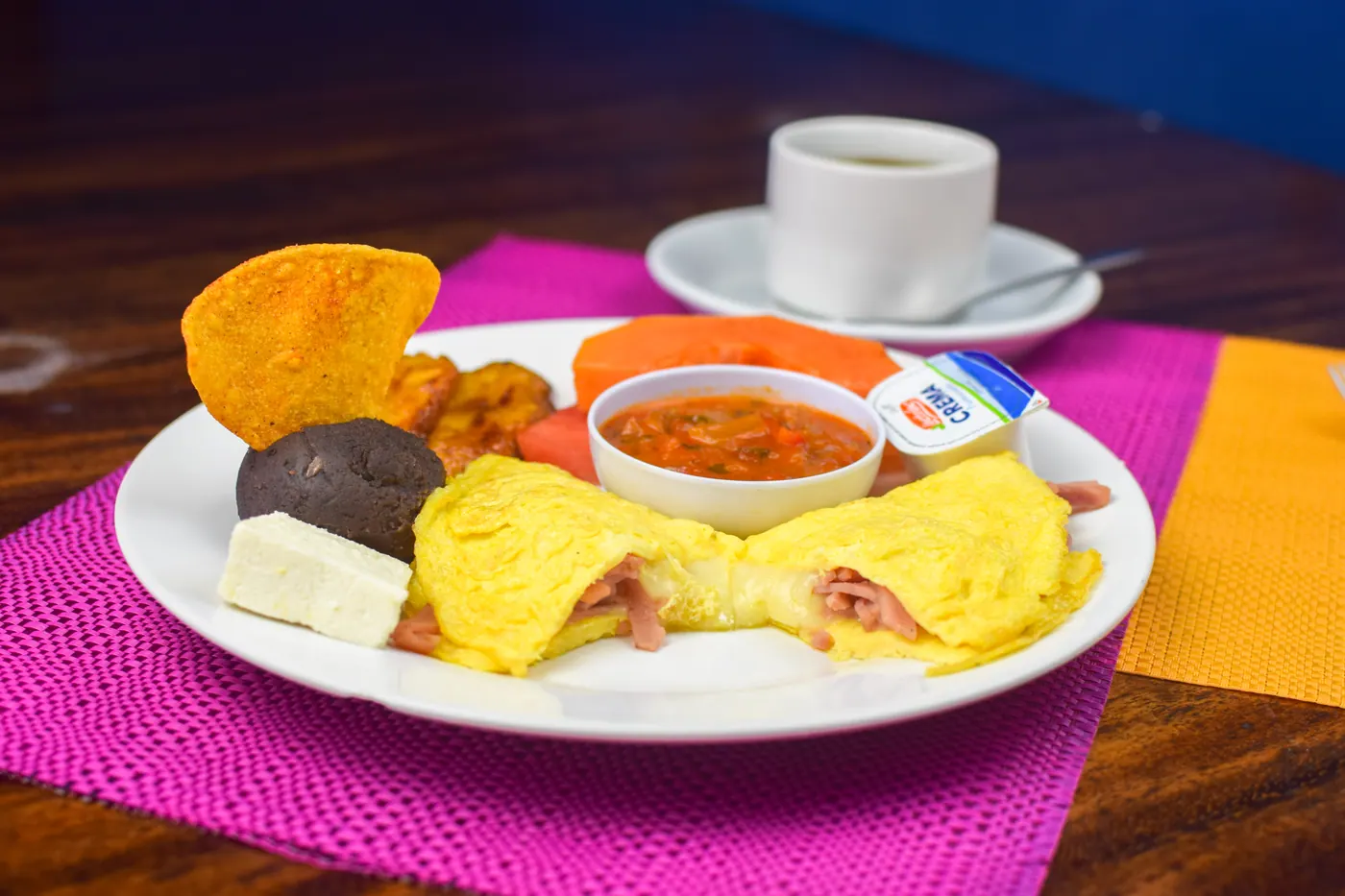 Desayuno típico con huevos, frijol, plátano, queso, salsa y café.